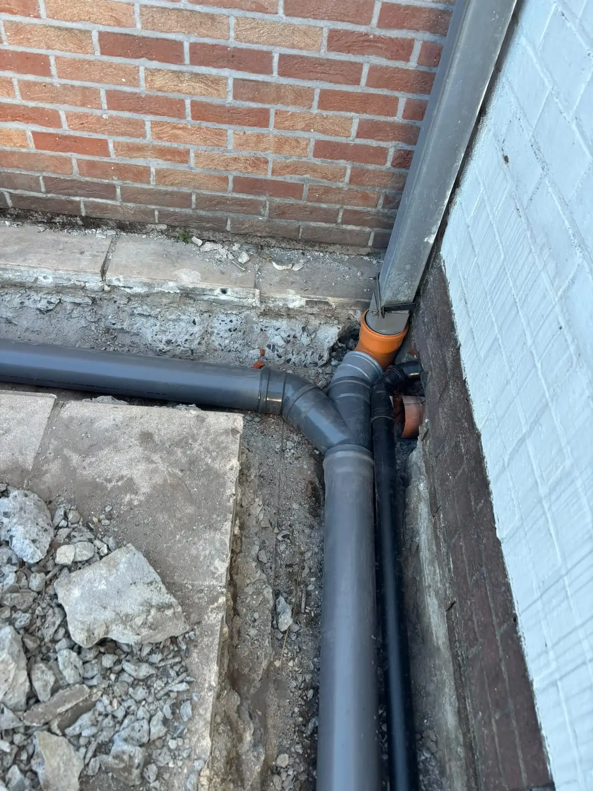 Nieuwe afvoerleiding langs de gevel aangesloten op de regenpijp in Zwijnaarde